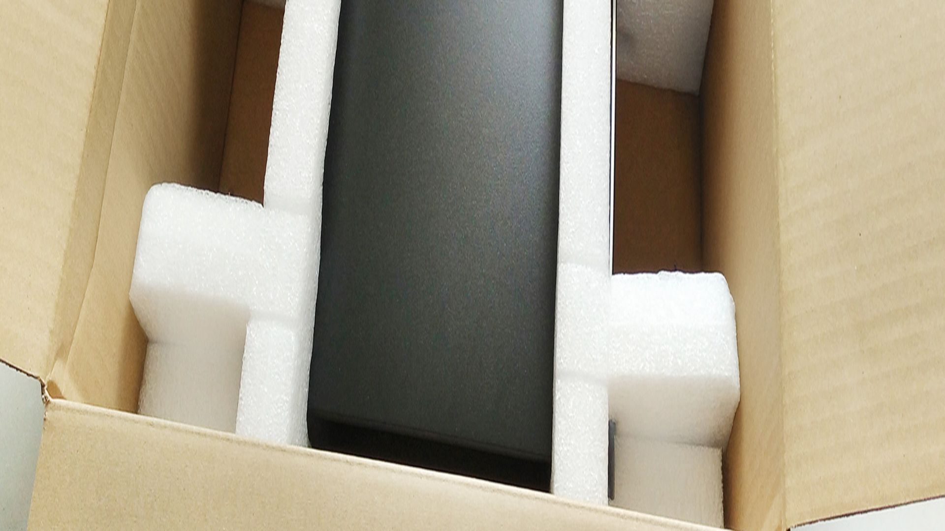schwarzes Ger&auml;t von wei&szlig;em Verpackungsschaum in einem Karton gesichert