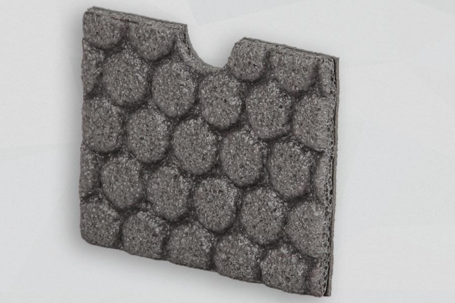 Poliüretan sünger Cello® TR100 Graue Schaumstoffplatte mit Noppenmuster stehend vor grauem Hintergrund